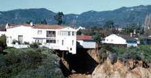 Figure 1 is a photograph showing a house perched precariously above a landslide.